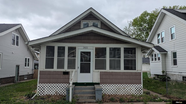 rear view of property featuring a sunroom, fence, and entry steps