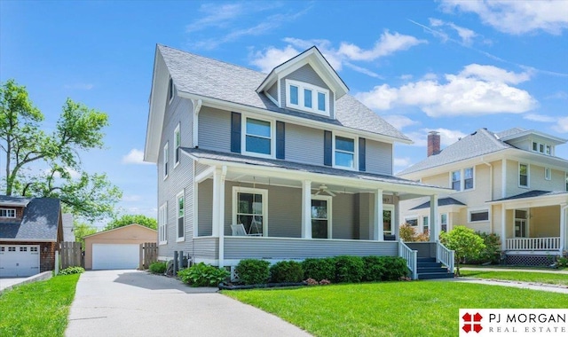 american foursquare style home featuring covered porch, a front yard, an outbuilding, and a garage