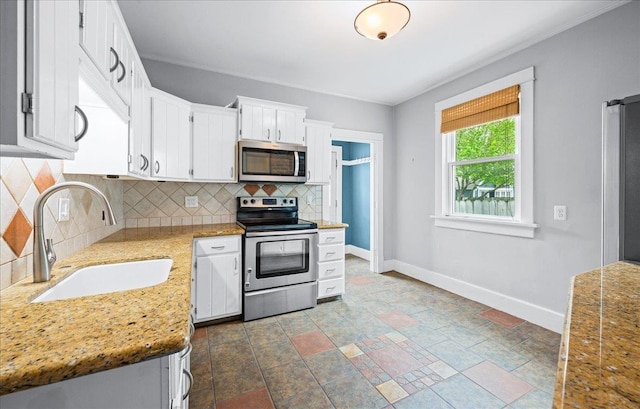 kitchen featuring appliances with stainless steel finishes, a sink, baseboards, decorative backsplash, and crown molding