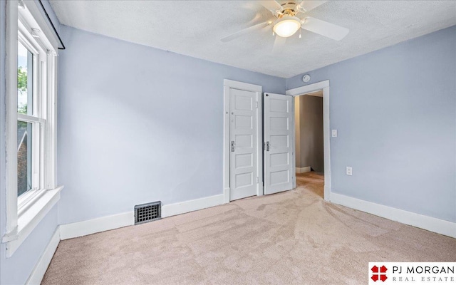 unfurnished bedroom with carpet flooring, baseboards, a textured ceiling, and a ceiling fan