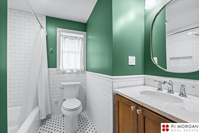full bathroom featuring tile walls, wainscoting, toilet, vanity, and shower / bath combo
