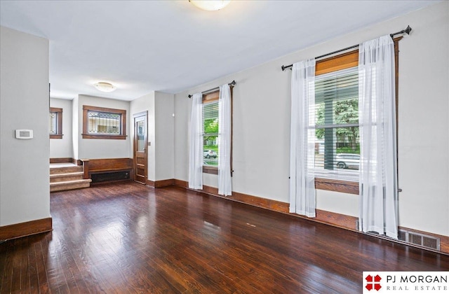 spare room with wood finished floors, stairway, and baseboards