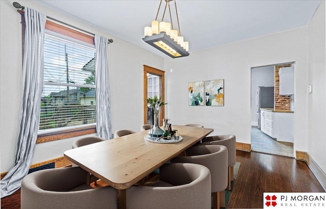 dining space with dark wood-type flooring, a chandelier, and baseboards