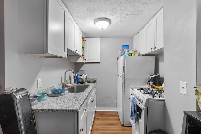 405 N 25th St, Lincoln, NE 68503 - kitchen with a textured ceiling, light wood-type flooring, a sink, white cabinets, and white range with gas cooktop