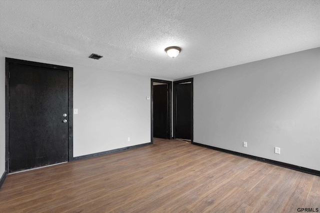 405 N 25th St, Lincoln, NE 68503 - empty room featuring baseboards, a textured ceiling, wood finished floors, and visible vents