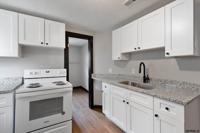 405 N 25th St, Lincoln, NE 68503 - kitchen featuring wood finished floors, white electric range, a textured ceiling, white cabinets, and a sink