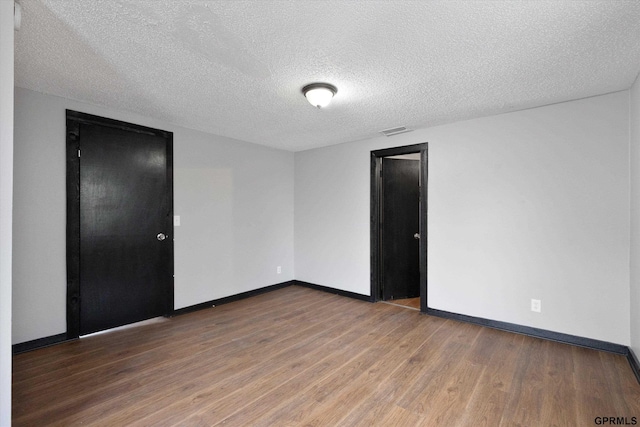 405 N 25th St, Lincoln, NE 68503 - empty room with baseboards, a textured ceiling, wood finished floors, and visible vents