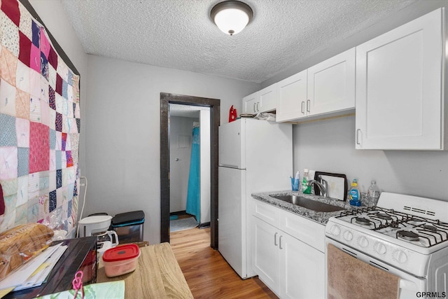 405 N 25th St, Lincoln, NE 68503 - kitchen with a sink, white appliances, a textured ceiling, light wood-style flooring, and white cabinetry