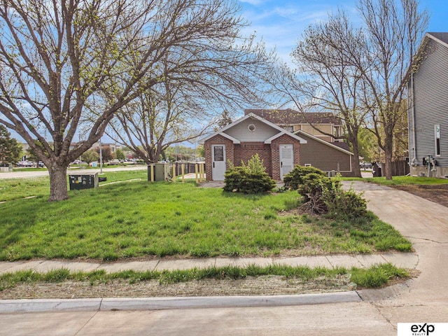 view of front of property with driveway, a front lawn, and brick siding