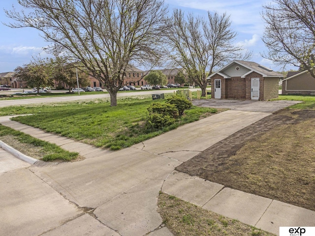 view of front of house featuring brick siding, a front lawn, driveway, and a residential view