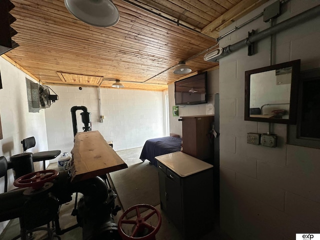 misc room with concrete floors, concrete block wall, and wooden ceiling