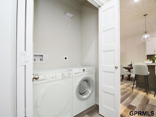 laundry room with laundry area, washing machine and dryer, and light wood-type flooring