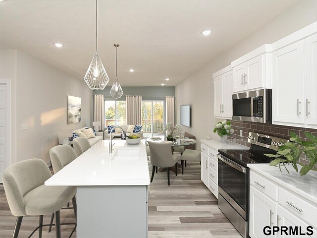 kitchen with a kitchen bar, light wood-type flooring, a sink, open floor plan, and stainless steel appliances