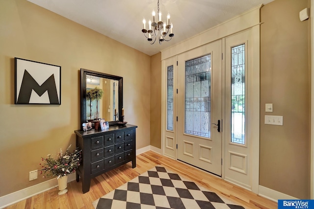 entrance foyer featuring a chandelier, wood finished floors, and baseboards