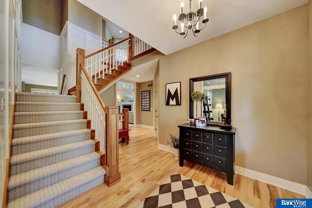 staircase featuring wood finished floors, a chandelier, baseboards, recessed lighting, and a high ceiling