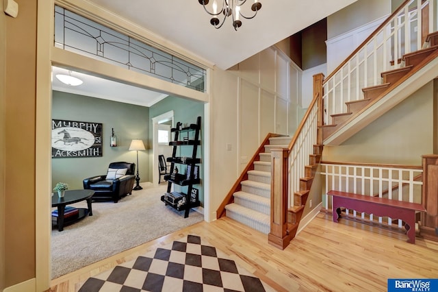 stairs with wood finished floors, crown molding, and a chandelier