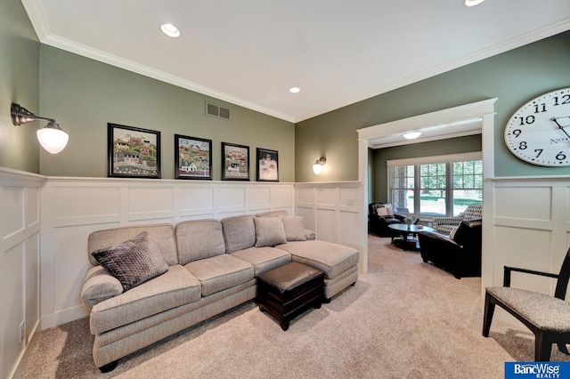 carpeted living room featuring a decorative wall, crown molding, and wainscoting