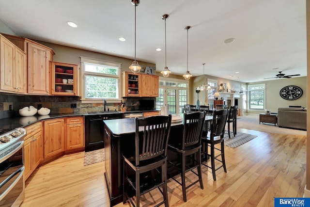 kitchen with dark countertops, a sink, light wood-type flooring, dishwasher, and range with two ovens