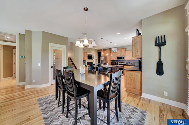 dining space with light wood-type flooring, baseboards, a chandelier, and recessed lighting
