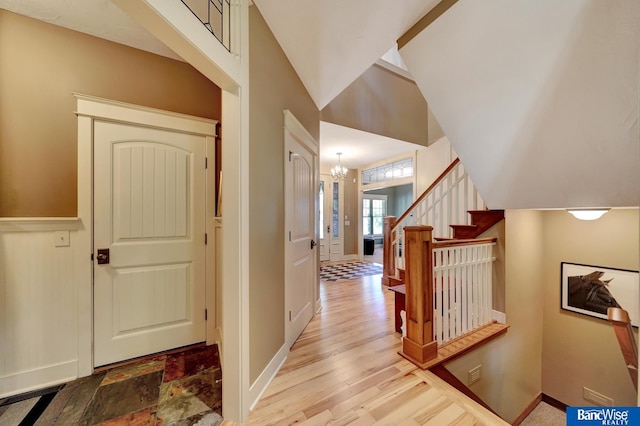 foyer featuring a chandelier, stairway, baseboards, and wood finished floors