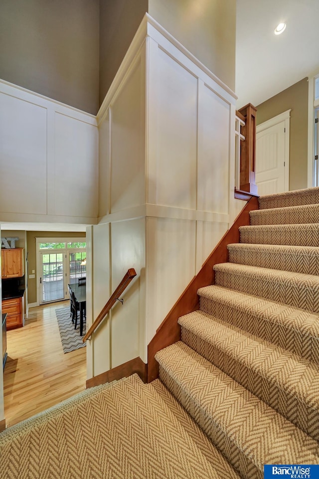 staircase with wood finished floors and recessed lighting