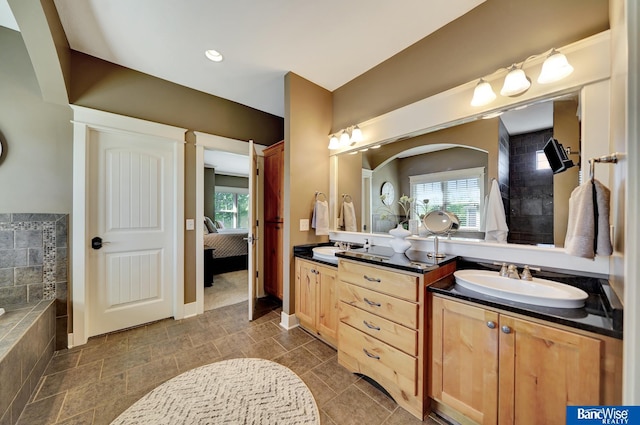 full bathroom featuring healthy amount of natural light, double vanity, ensuite bath, and baseboards
