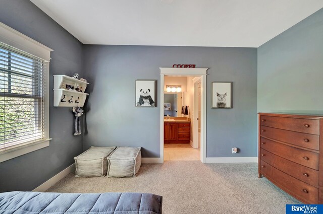 carpeted bedroom featuring baseboards and ensuite bath