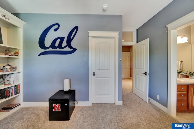 bedroom with light carpet, a sink, and baseboards