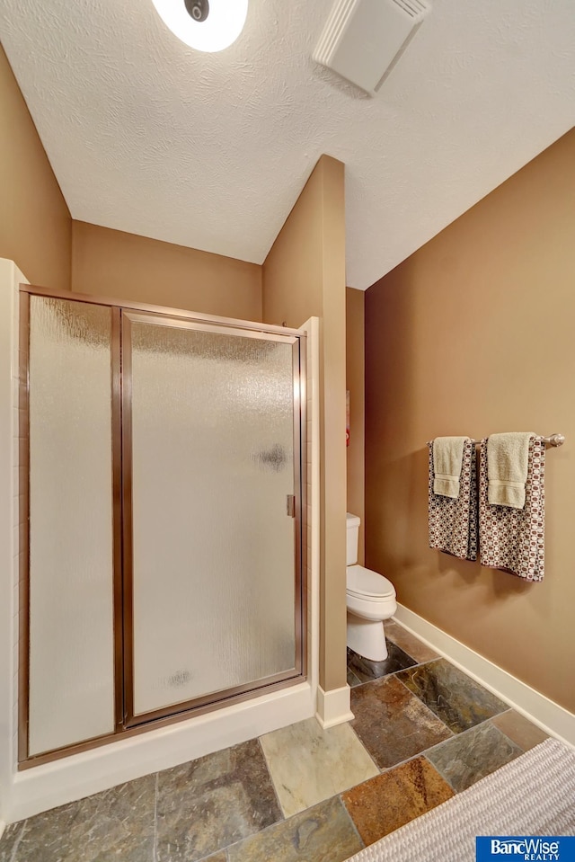 full bath with stone tile flooring, baseboards, a stall shower, and toilet