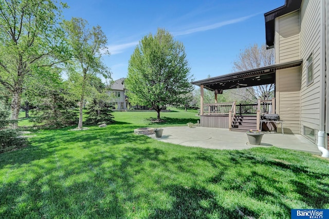 view of grassy yard featuring a patio and a deck