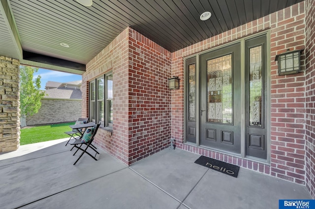 doorway to property featuring brick siding and covered porch