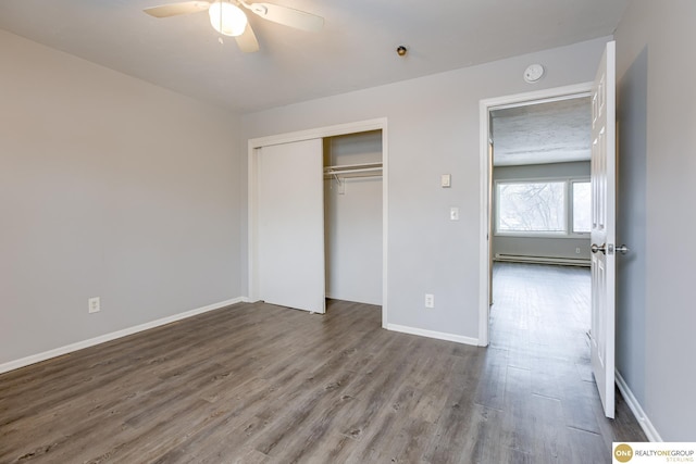 unfurnished bedroom with a ceiling fan, baseboards, wood finished floors, a baseboard radiator, and a closet