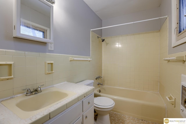 full bath with vanity, toilet, tile patterned floors, tile walls, and  shower combination