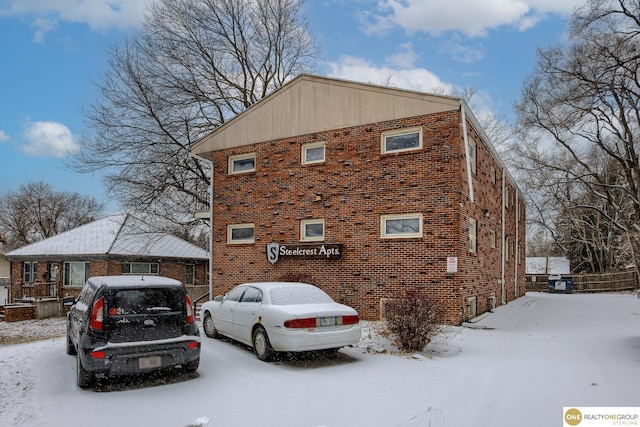 snow covered property with brick siding
