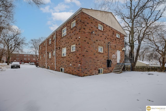 view of snowy exterior featuring brick siding