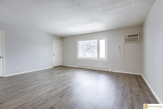empty room with wood finished floors, a baseboard heating unit, a textured ceiling, and an AC wall unit