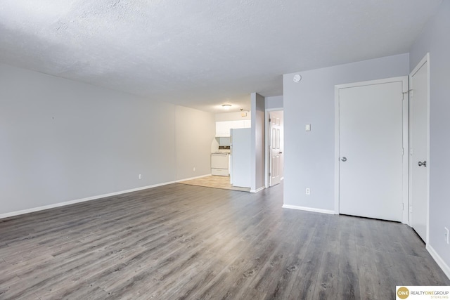 unfurnished living room with baseboards, a textured ceiling, and wood finished floors