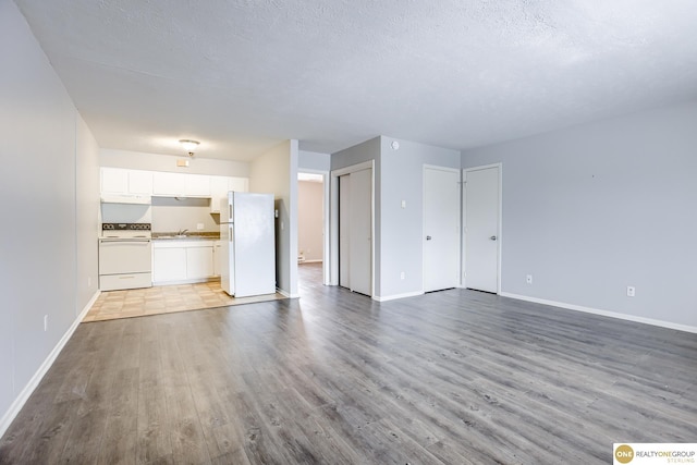 unfurnished living room with baseboards, a textured ceiling, and wood finished floors
