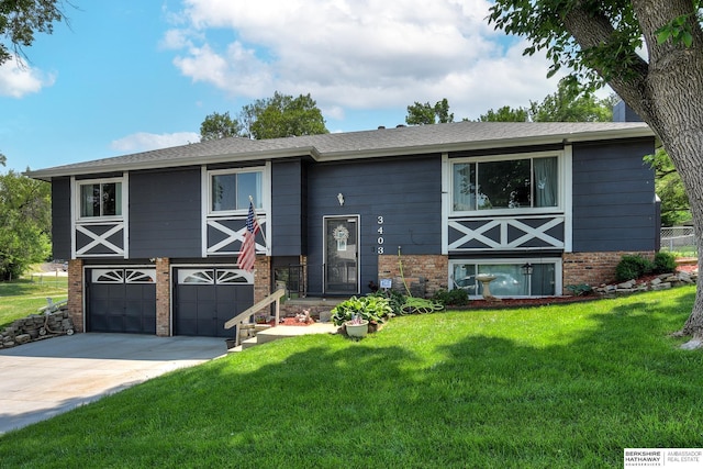 raised ranch with concrete driveway, brick siding, a front yard, and a garage