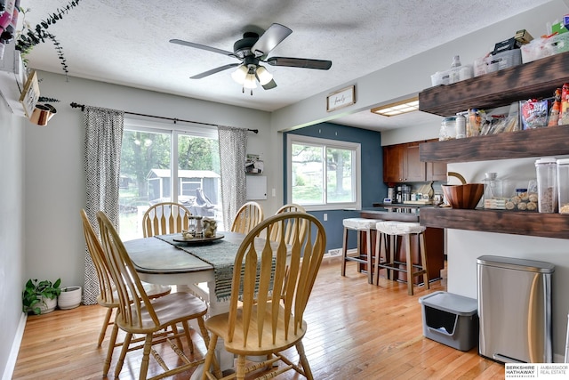 dining area with a textured ceiling, light wood-style flooring, and a wealth of natural light