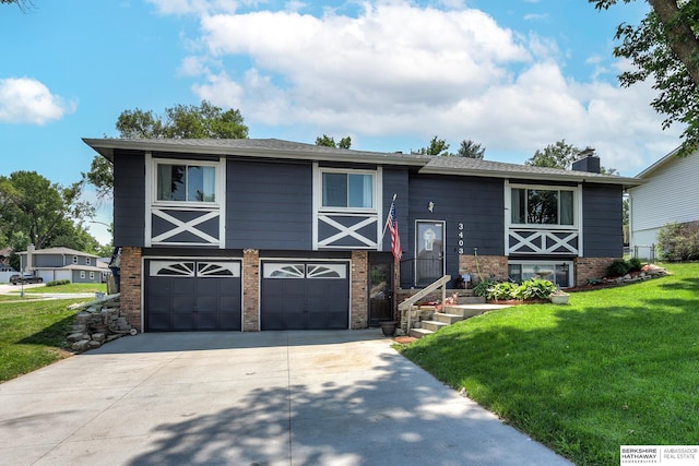 bi-level home featuring concrete driveway, brick siding, an attached garage, and a front lawn