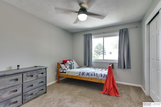 bedroom featuring a textured ceiling, baseboards, light carpet, and a closet