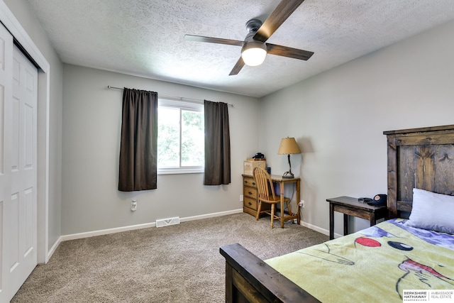 carpeted bedroom with ceiling fan, a textured ceiling, baseboards, visible vents, and a closet