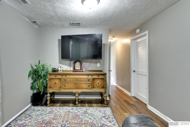 sitting room featuring a textured ceiling, baseboards, visible vents, and wood finished floors