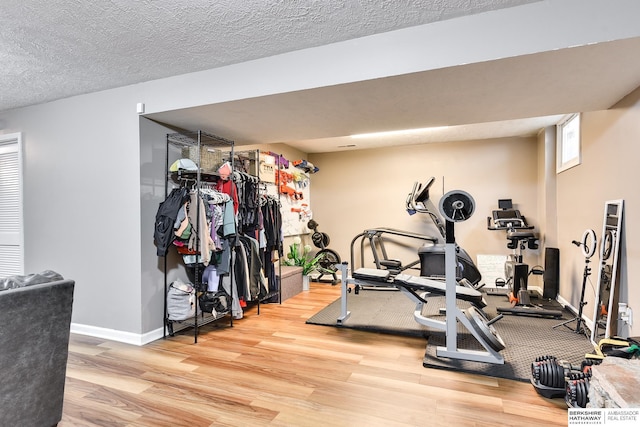 workout area featuring a textured ceiling, baseboards, and wood finished floors