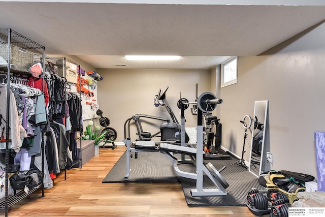 workout area with baseboards and wood finished floors