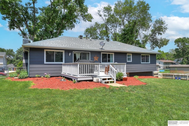 rear view of property featuring a chimney, a wooden deck, fence, a yard, and a shingled roof