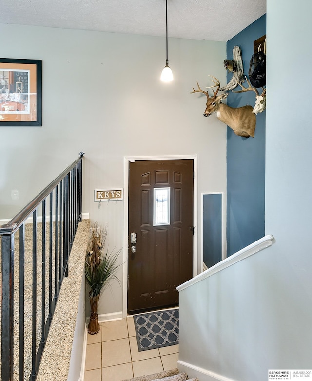 foyer with baseboards, stairs, and light tile patterned floors