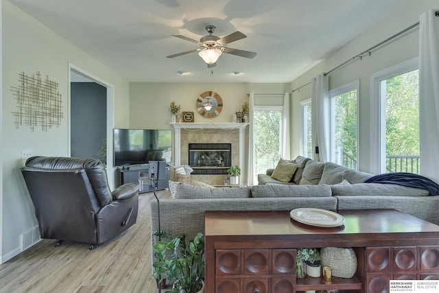 living area featuring ceiling fan, visible vents, a fireplace, baseboards, and light wood finished floors