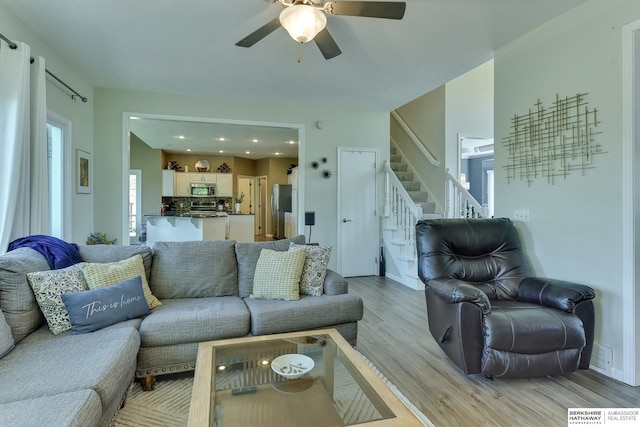 living room with stairs, a ceiling fan, recessed lighting, and light wood-style floors